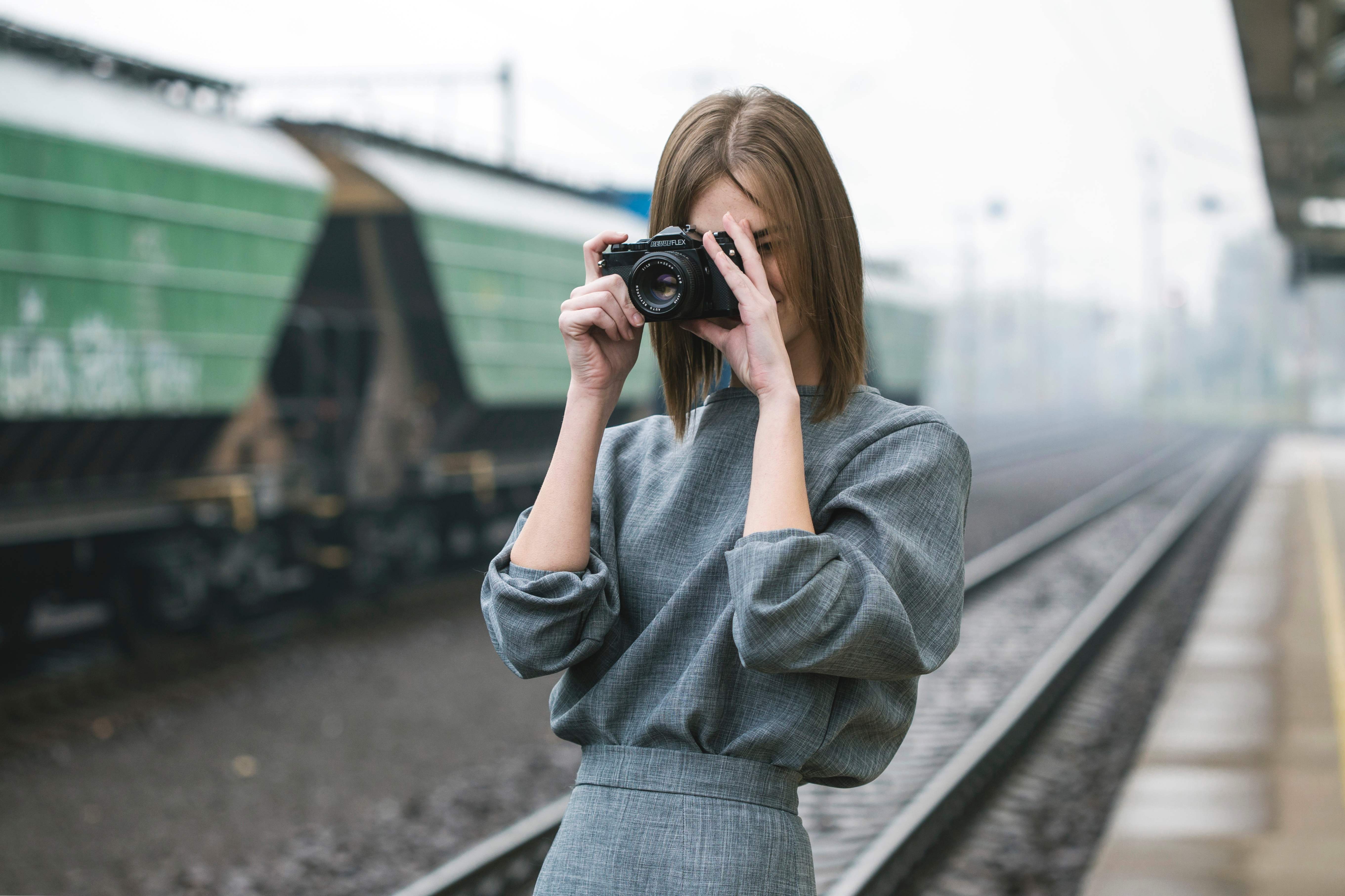 Фотографировать на расстоянии. Девушка с фотоаппаратом в поезде. Девушка с серым фотоаппаратом. Фотограф железная дорога. Девушка с фотоаппаратом сидит на дороге.